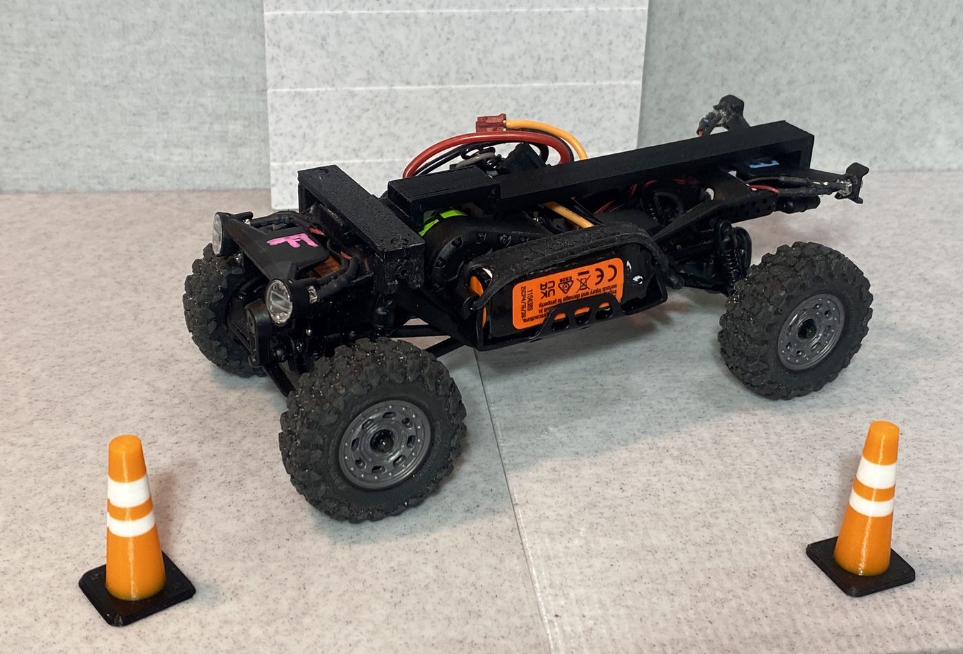 The spine rail installed on a bare SCX30 chassis, front three-quarter view with miniature traffic cones.